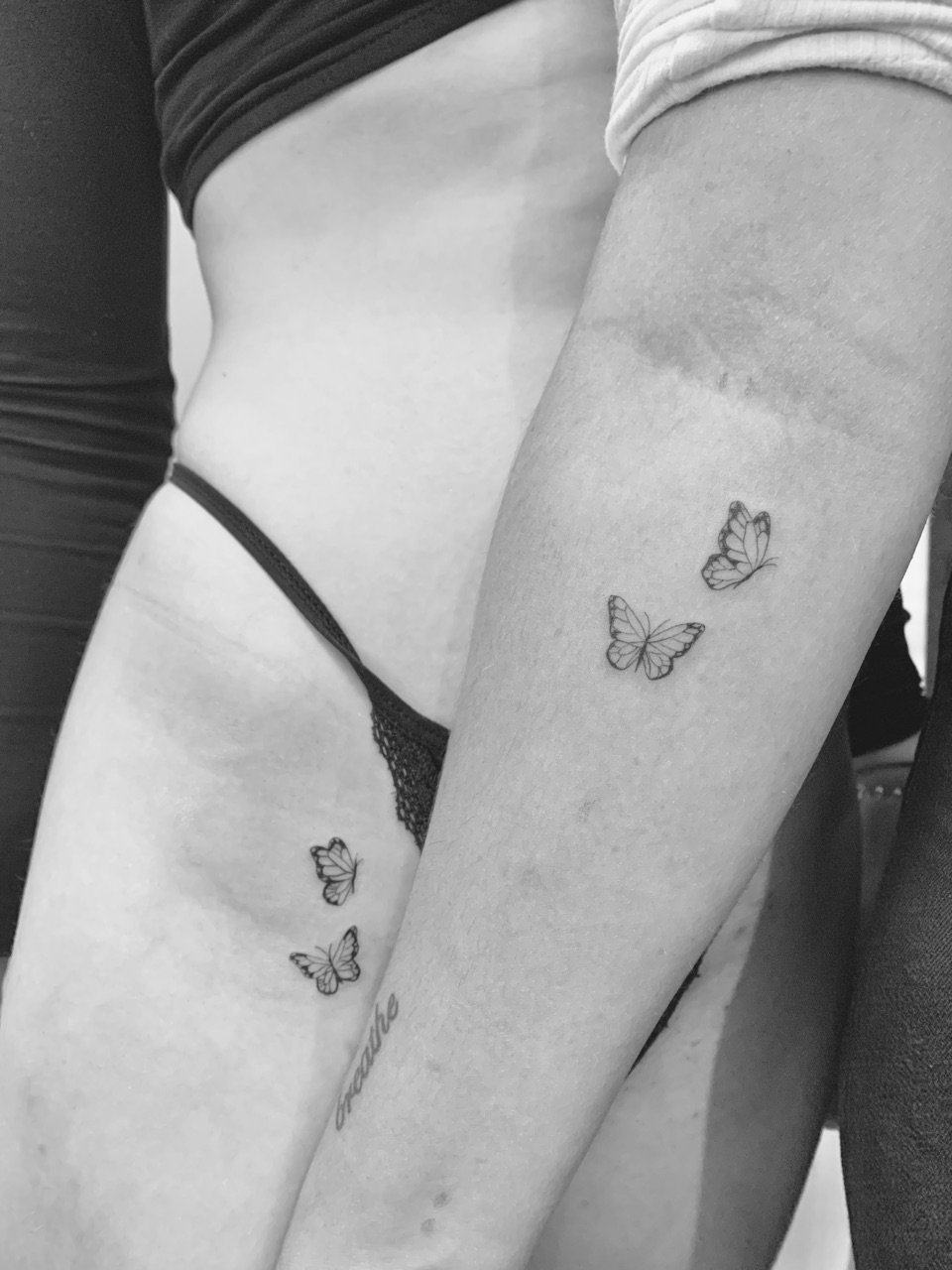 Tattoo of two small butterflies on a forearm, beside a second pair of small butterflies on another person